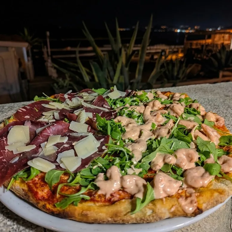 Due pizze fredde, bresaola e salmone, servite in terrazza di sera