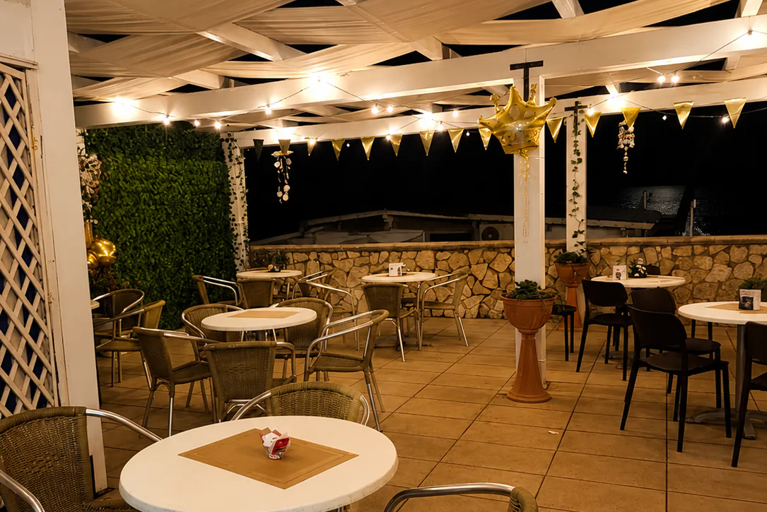 La terrazza di Alfa di sera, con le luci a filo e i festoni dorati accesi